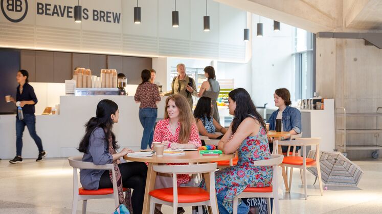 three individuals sit around a table in a modern building chatting